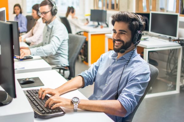 Handsome male customer service executive working at office with his colleagues